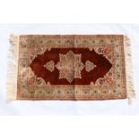 Iranian silk rug, brown field centred with a fawn medallion, fawn spandrels and palmette border,