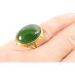Nephrite dress ring, cabochon stone measuring approx. 18mm x 12mm, in an unmarked gold collet