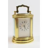 Miniature brass carriage timepiece, late 20th Century, oval form, white enamel dial with Roman