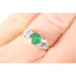 Emerald and diamond three stone ring, the central round cut emerald of approx. 0.75ct, flanked by