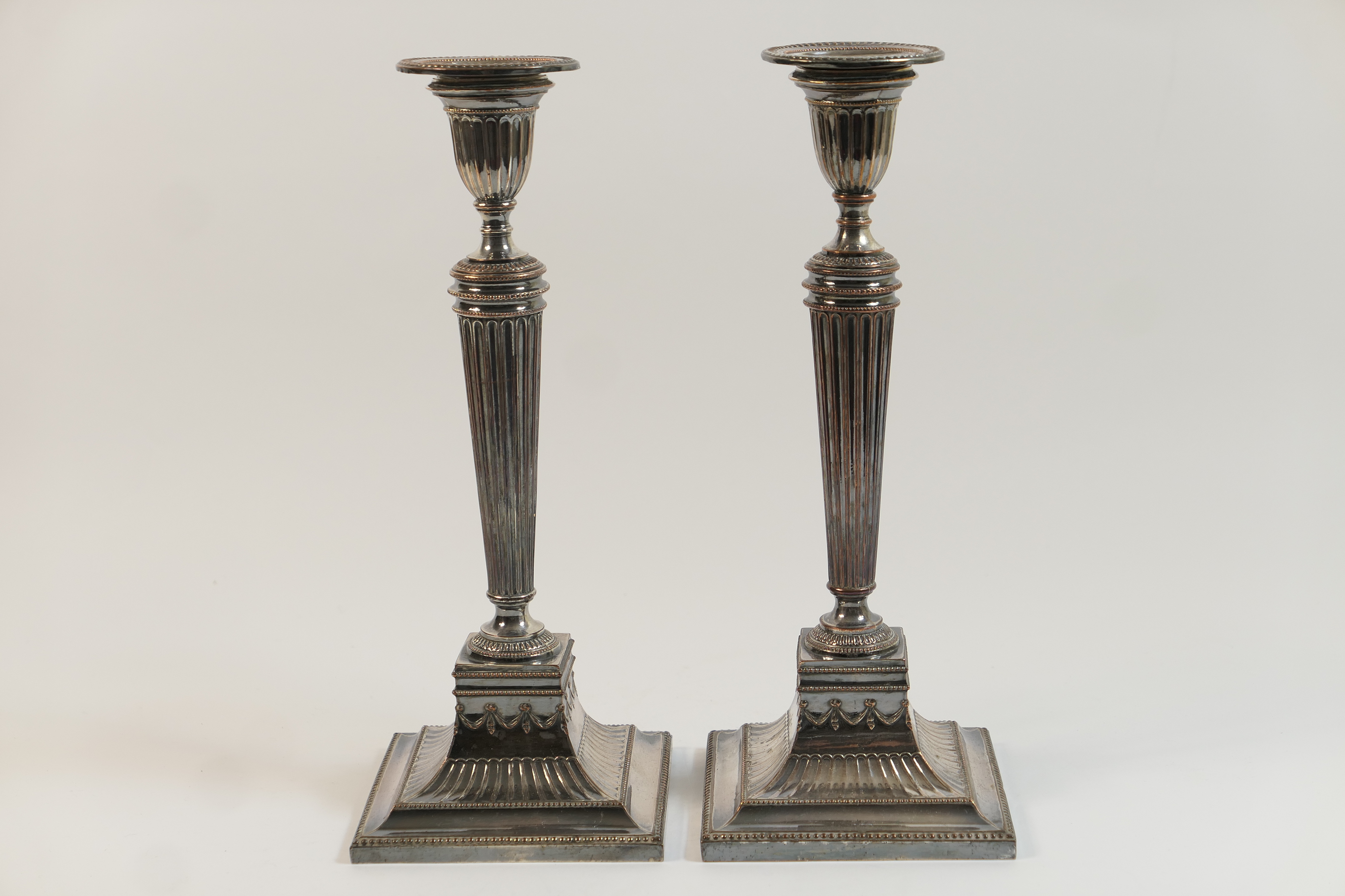 Pair of old Sheffield plated candlesticks, circa 1800, having a fluted urn shaped sconce with