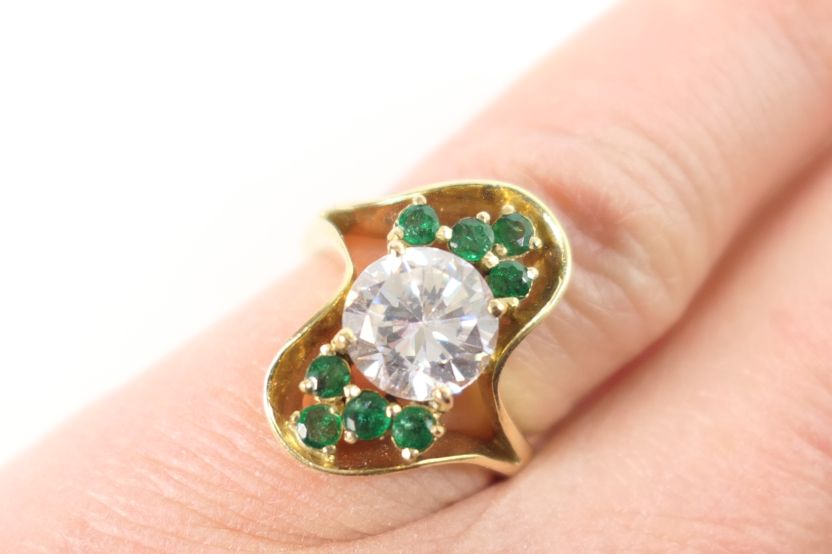 Emerald and cubic zirconia cluster ring, the central brilliant cut white stone bordered with small