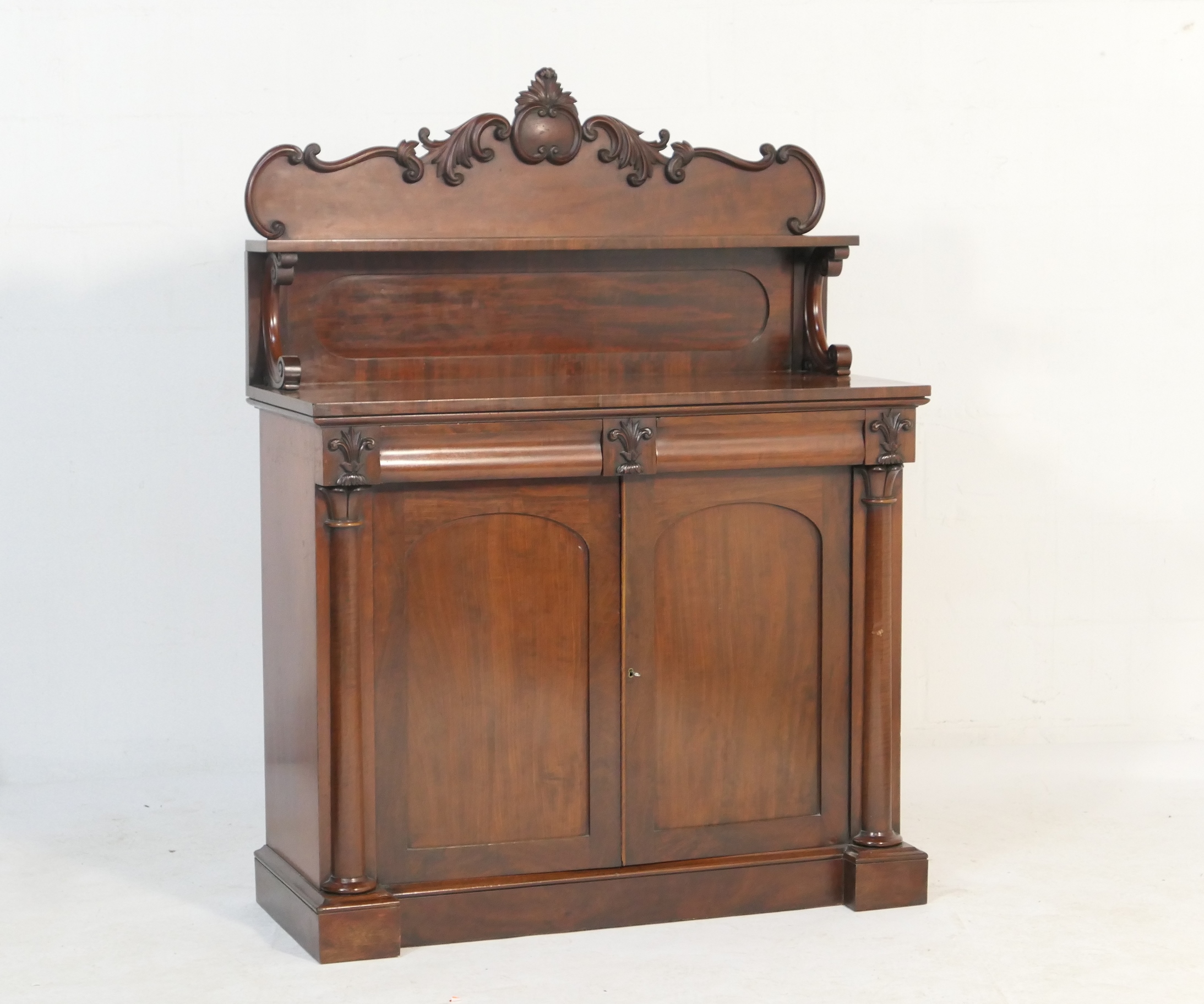 Victorian mahogany chiffonier, circa 1860, having a carved panel back with a shelf over a base