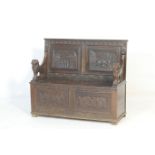 Carved oak box settle, first quarter 20th Century, the back having two figural carved panels with '
