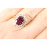 Ruby and diamond cluster ring, the oval cut ruby of approx. 1.5cts, measuring 11mm x 6mm, in