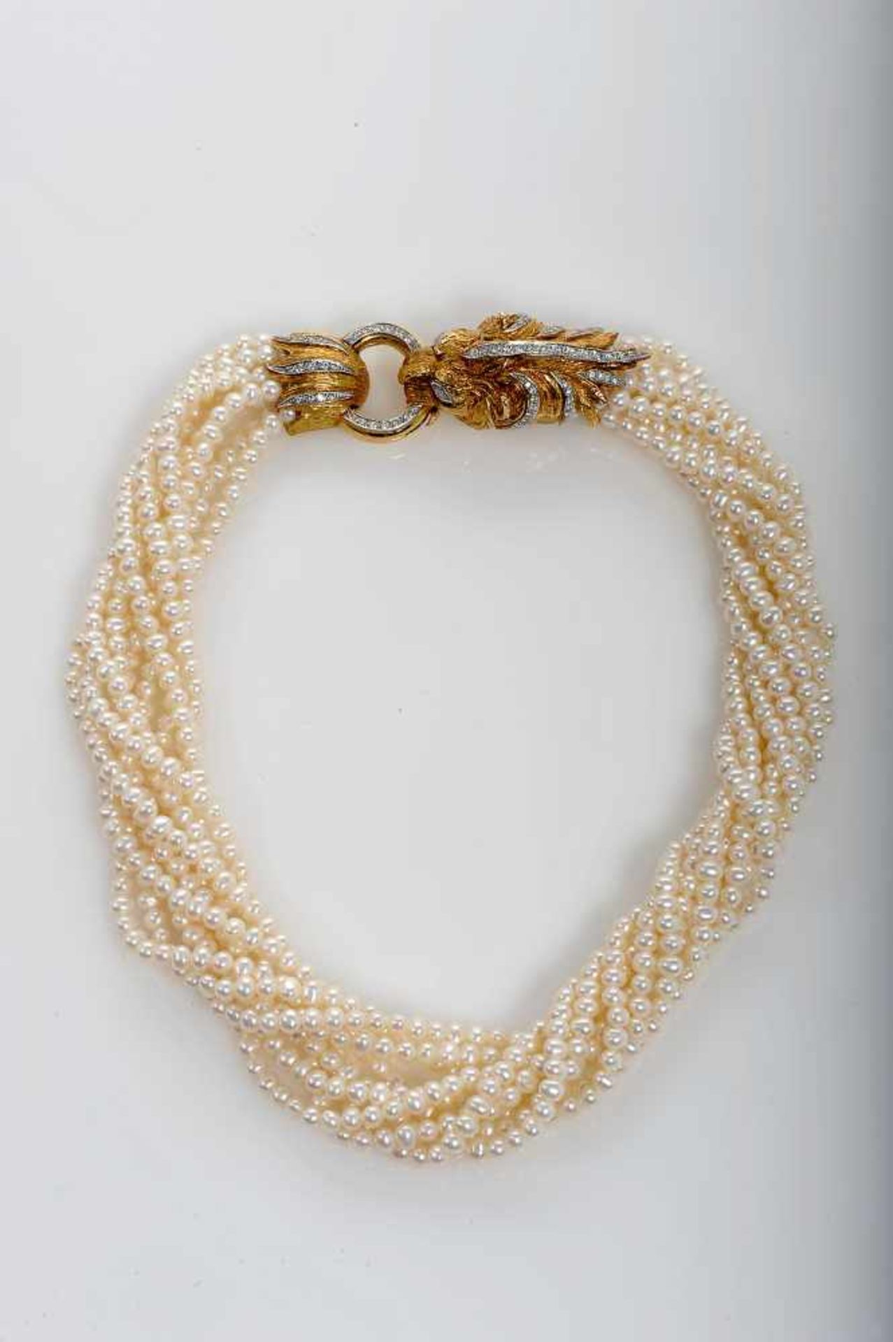 A Necklace, nine strings of culture pearls, bicolour gold clasp, carved decoration "Lion fauce", set