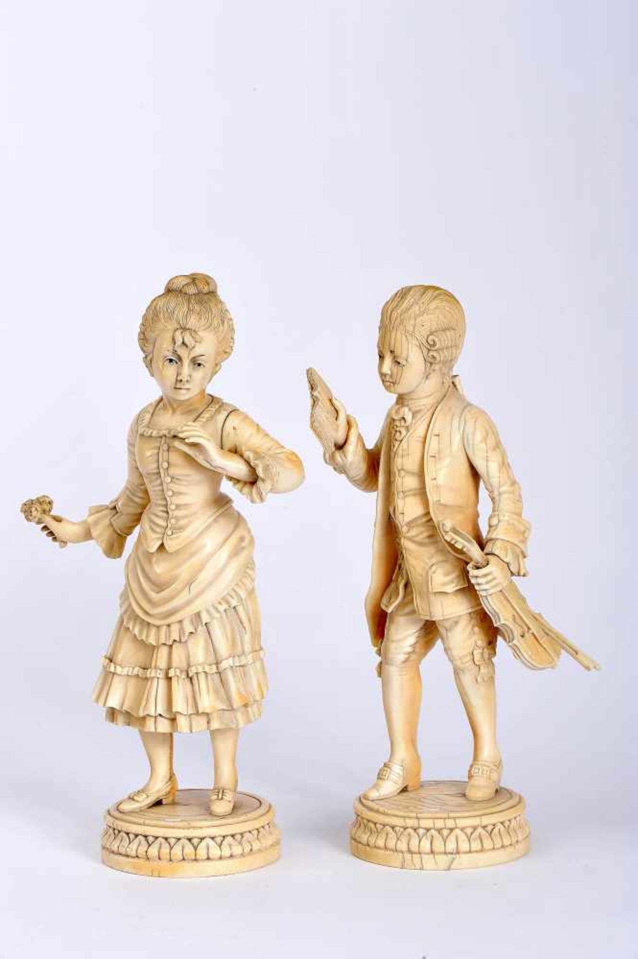 A Girl with Flower and Musician, a pair of ivory sculptures, European, 19th/20th C., a finger on