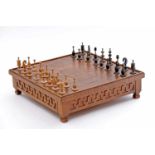 A Board with Chess Pieces, walnut board with drawer and four feet, sides en relief "Greek