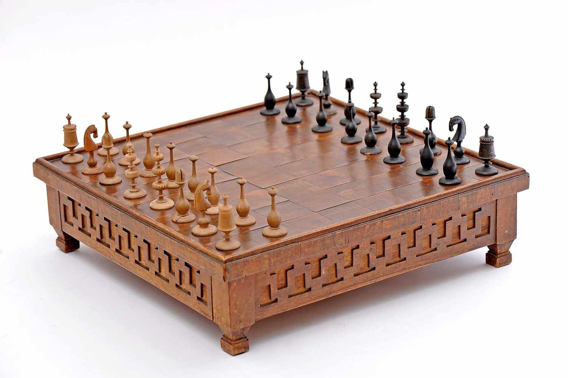 A Board with Chess Pieces, walnut board with drawer and four feet, sides en relief "Greek
