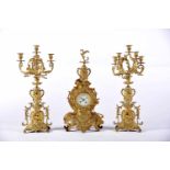 A Garniture - Table Clock and a Pair of Five-light Candelabra, Napoleon III, gilt metal en relief,