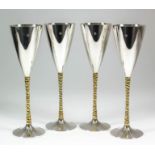 A set of four Elizabeth II silver and silver gilt champagne flutes, the plain conical bowls with