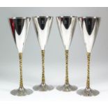 A set of four Elizabeth II silver and silver gilt champagne flutes, the plain conical bowls with