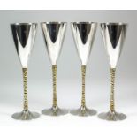 A set of four Elizabeth II silver and silver gilt champagne flutes, the plain conical bowls with