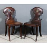 A pair of George III mahogany hall chairs, the shaped backs with reeded scroll mouldings, circular