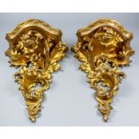 A pair of early 20th Century Italian carved giltwood wall brackets of shaped outline, supported on