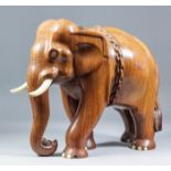 An Indian carved teak and bone inlaid standing elephant with chain around its body, 12.25ins high