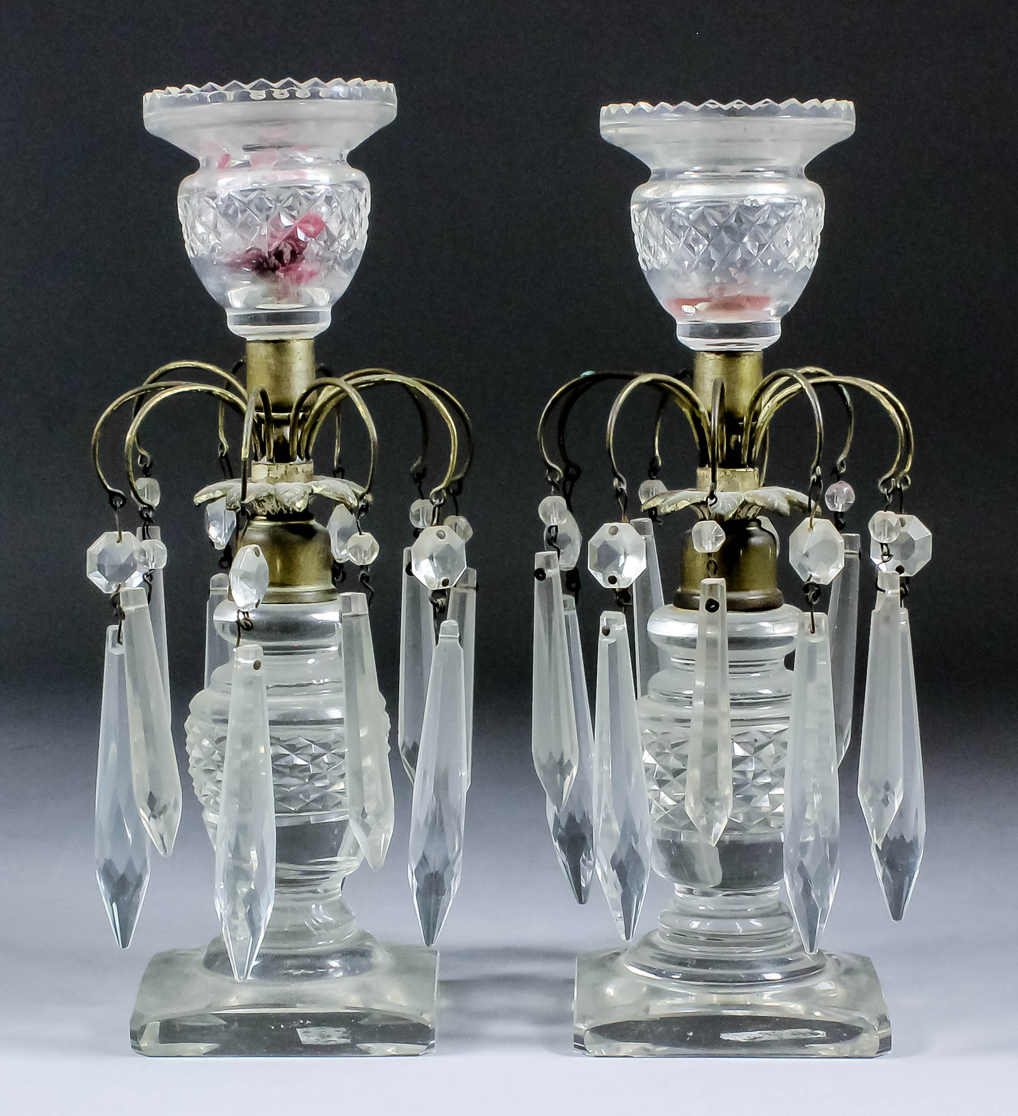 A pair of early 19th Century cut glass and silvered brass pillar candlesticks hung with cut