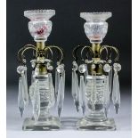 A pair of early 19th Century cut glass and silvered brass pillar candlesticks hung with cut