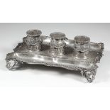 An Edward VII silver rectangular ink stand of shaped outline with gadroon and scroll mounts, two pen