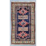 A Kazak Karachop rug woven in colours with three angular medallions interspersed by rectangular