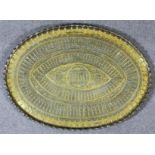 A Persian oval brass tray with repousse decoration of standing male figures with spears, the edge of