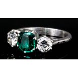 A platinum mounted three stone emerald and diamond ring, set with a central octagonal cut emerald (