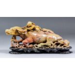 A Chinese carved soapstone group of a reclining water buffalo with two figures on its back and