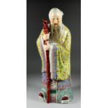 A Chinese porcelain figure of a standing sage with staff, 23.5ins high, two impressed seal marks