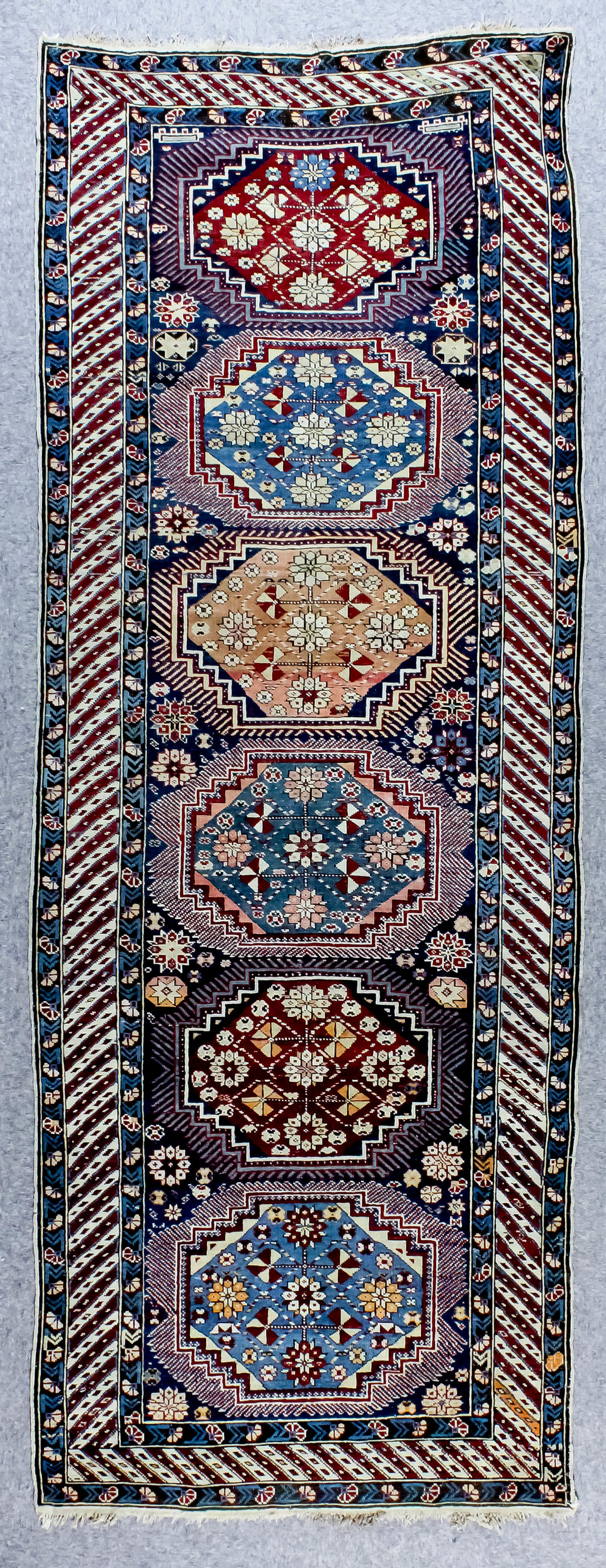 A Kazak runner woven in colours with six bold octagonal motifs, filled with stylised floral ornament