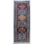 A Kazak runner woven in colours with six bold octagonal motifs, filled with stylised floral ornament