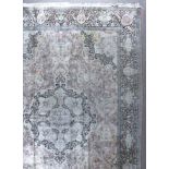 An Eastern silk carpet woven in pastel shades with a bold central medallion filled with flowers