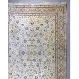 A Kirman carpet woven in pastel shades of navy blue, pale blue and fawn, with trailing palmettes and