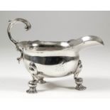 A good George II cast silver oval sauce boat with shaped rim and leaf capped flying scroll handle,
