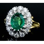An 18ct gold mounted emerald and diamond cluster ring, set with central oval cut emerald (