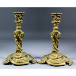 A pair of late 19th Century gilt brass candlesticks and drip pans of Baroque design, 10.25ins high