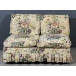 A late Victorian low two-seat settee with loose floral printed fabric, on turned front legs and