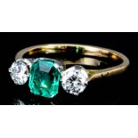 A gold coloured metal mounted three stone emerald and diamond ring, set with central rectangular cut