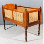 A Victorian mahogany and cane panelled cot with turned finials, solid arched top headboard and