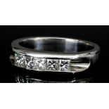 A modern 18ct white gold mounted diamond ring, channel set with five cushion cut diamonds (