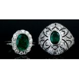 A modern 14ct white gold mounted emerald and diamond oval cluster ring, set with an oval emerald (