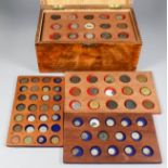 A stained wood storage box with fitted interior trays containing a mixed selection of silver, bronze