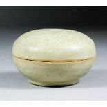 A Chinese celadon glazed circular box and cover, 3.75ins (9.5cm) x 2.5ins (6.4cm) high