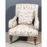 A late Victorian scroll back easy chair, upholstered in tapestry, the back buttoned, with scroll