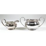 A George V silver circular two-handled sugar basin and matching milk jug, the bulbous bodies with