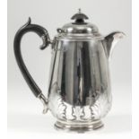 A George V silver hot water pot with slightly domed cover, the plain body with engraved leaf pattern