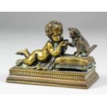 A 19th Century French bronze group of a reclining putti feeding a cat sitting on a rectangular