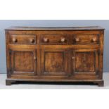 An early 19th Century panelled oak dresser base with plain top, fitted three frieze drawer with