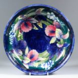 A Moorcroft pottery shallow bowl, tube lined and decorated in colours with "Iris" design, on a