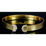 A modern 18ct gold mounted and diamond torque bracelet of reeded form, the shaped tips pave set with