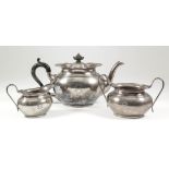 A George V silver three-piece tea service with plain oval bulbous bodies, the shaped rims with